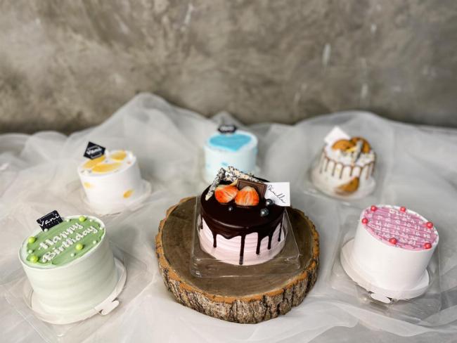 Một chiếc bánh kem tươi ảo đang được trang trí cầu kỳ trong trò chơi, với các lớp kem nhiều màu và topping đa dạng