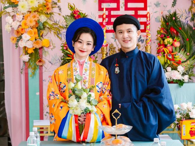 Cặp đôi và gia đình chụp ảnh kỷ niệm trước phông nền trang trí đám hỏi nhà gái rực rỡ, lưu giữ khoảnh khắc hạnh phúc.